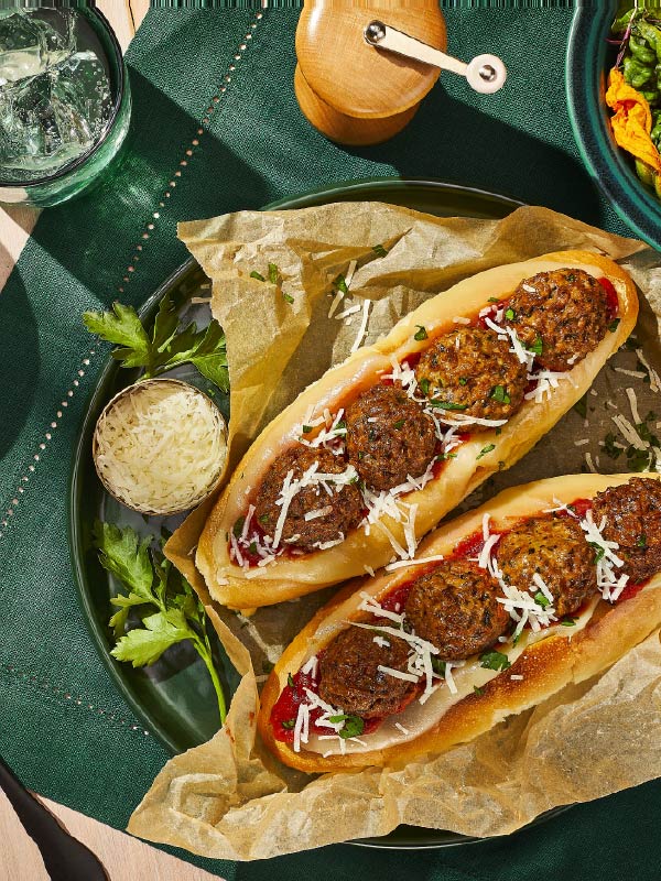 Two delicious meatball subs are covered in mozzarella cheese