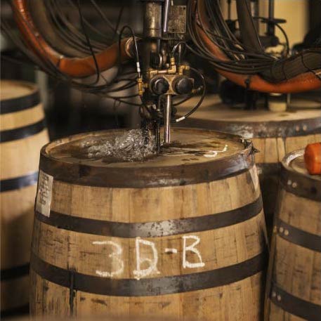 A whiskey barrel is tapped by a machine drill